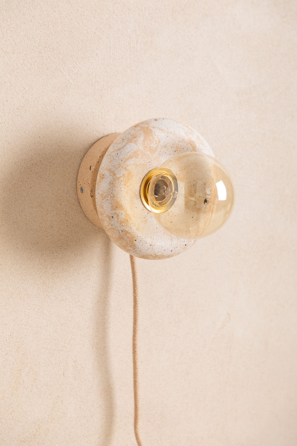 Applique murale en béton Nora, teinte Écume Sabbia. Douille E27 dorée en laiton. Câble en jute. Fabriqué par Atelier Hesmée.
