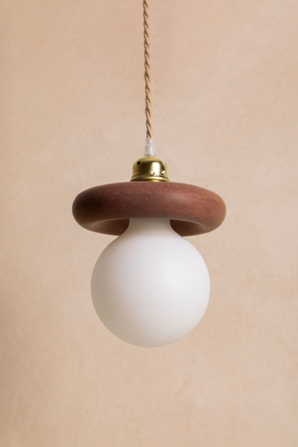 Suspension en béton Nora, teinte Moca. Douille E27 dorée en laiton. Câble en jute. Fabriqué par Atelier Hesmée.