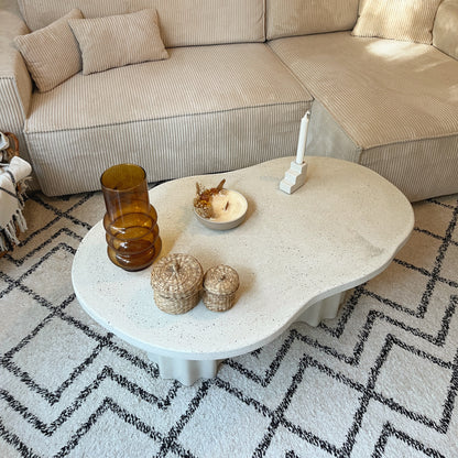 Table basse en béton Hestia. Elle a un plateau organique et deux pieds cannelés. Fabriquée sur-mesure par Atelier Hesmée.